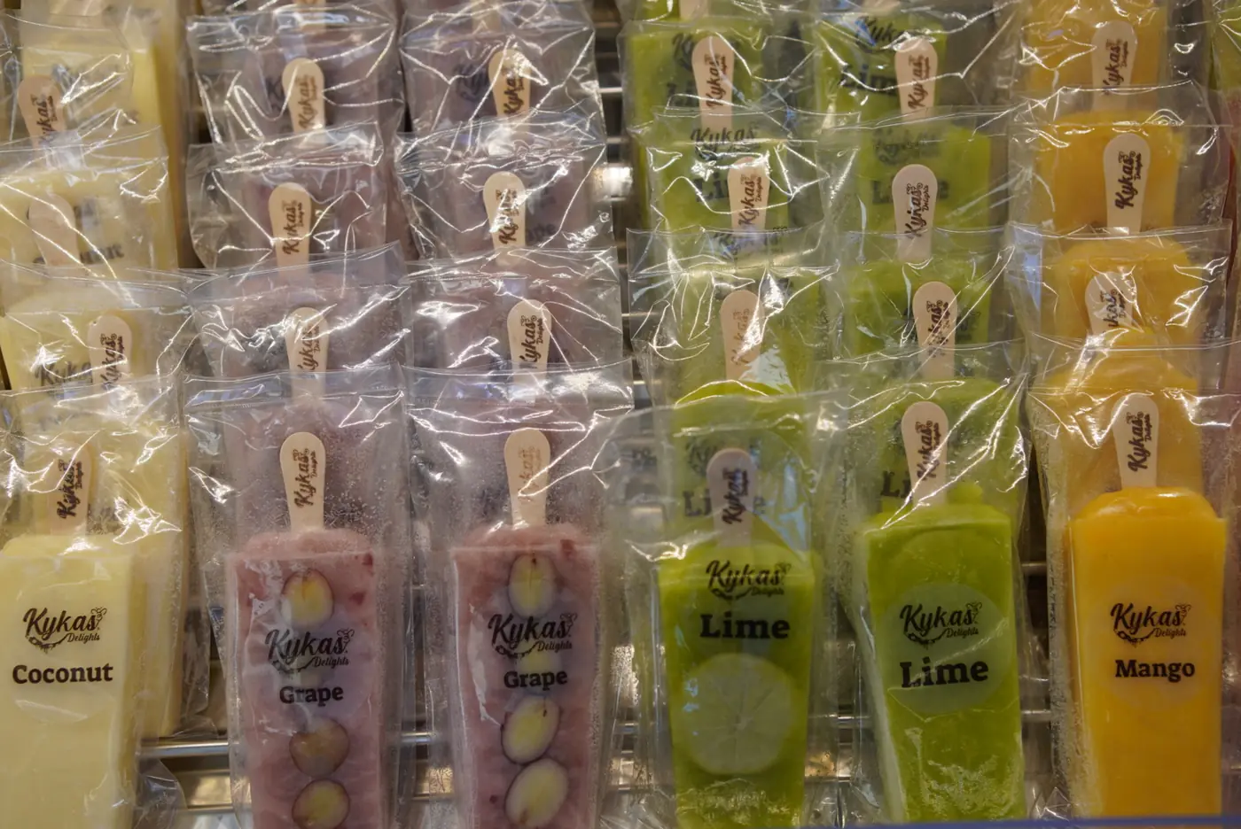 Rows of coconut, grape, lime and mango paletas in the freezer